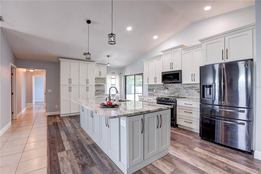 1418 Buckner Road Valrico, FL 33596 - Photo 17 of 37 a kitchen with stainless steel appliances kitchen island granite countertop a refrigerator a stove and a sink with wooden floor