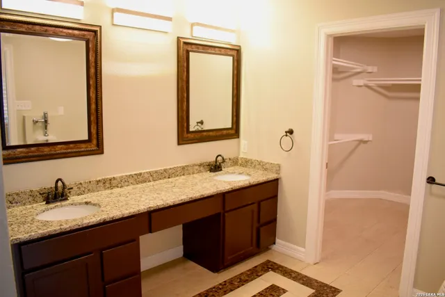 a bathroom with a granite countertop double vanity sink and mirror