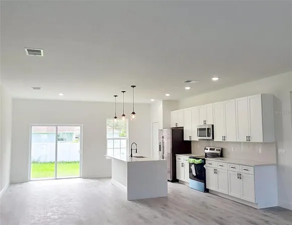 a large kitchen with stainless steel appliances kitchen island a large counter top a sink a stove and a refrigerator