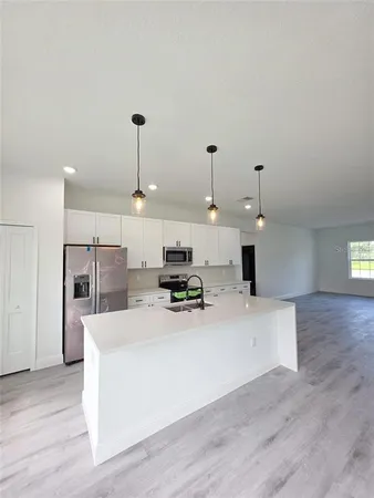 a kitchen with stainless steel appliances a stove top oven a refrigerator and white cabinets with wooden floor