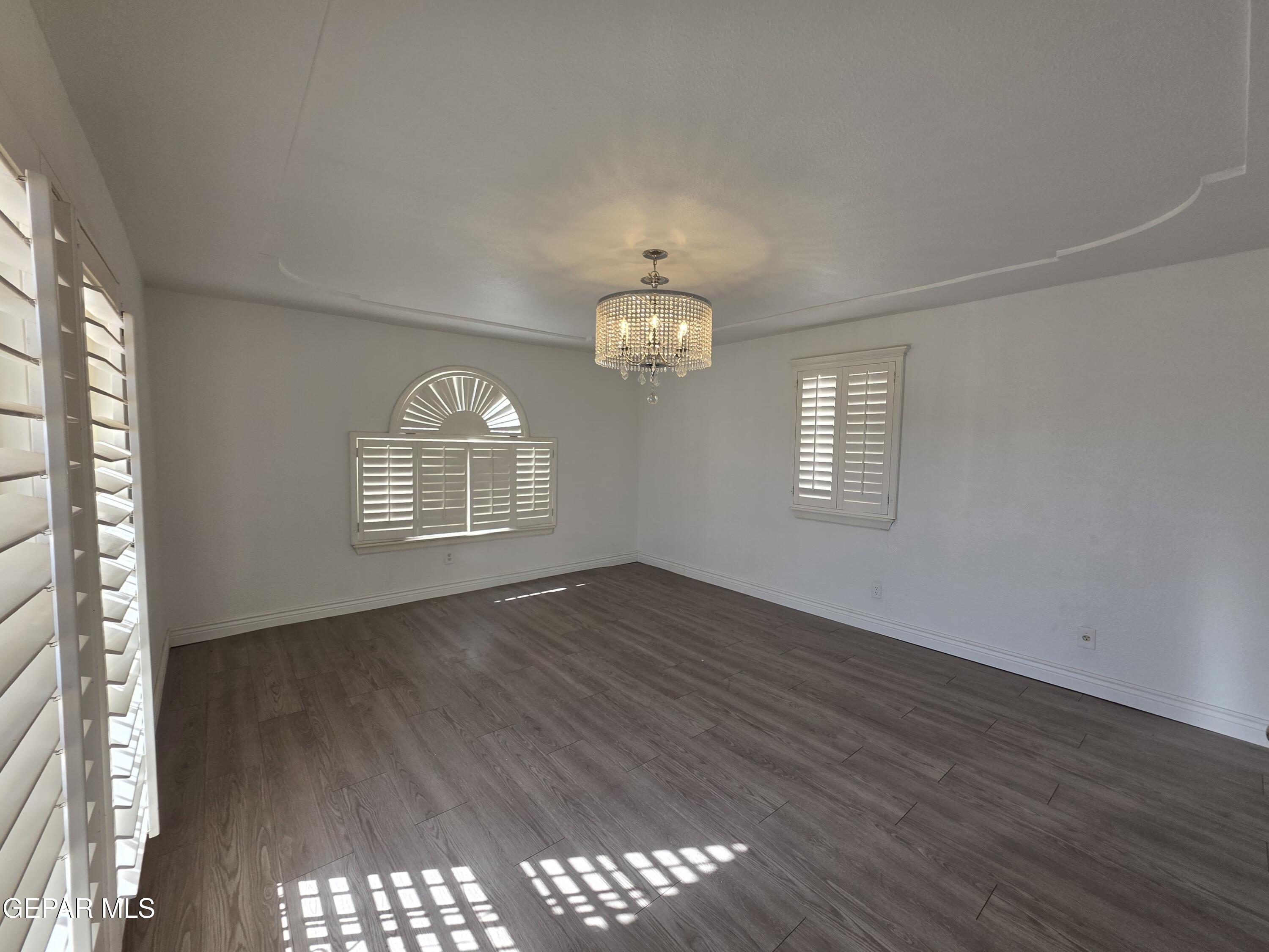 11661 Socorro Road Socorro, TX 79927 - Photo 18 of 32 an empty room with wooden floor chandelier and windows