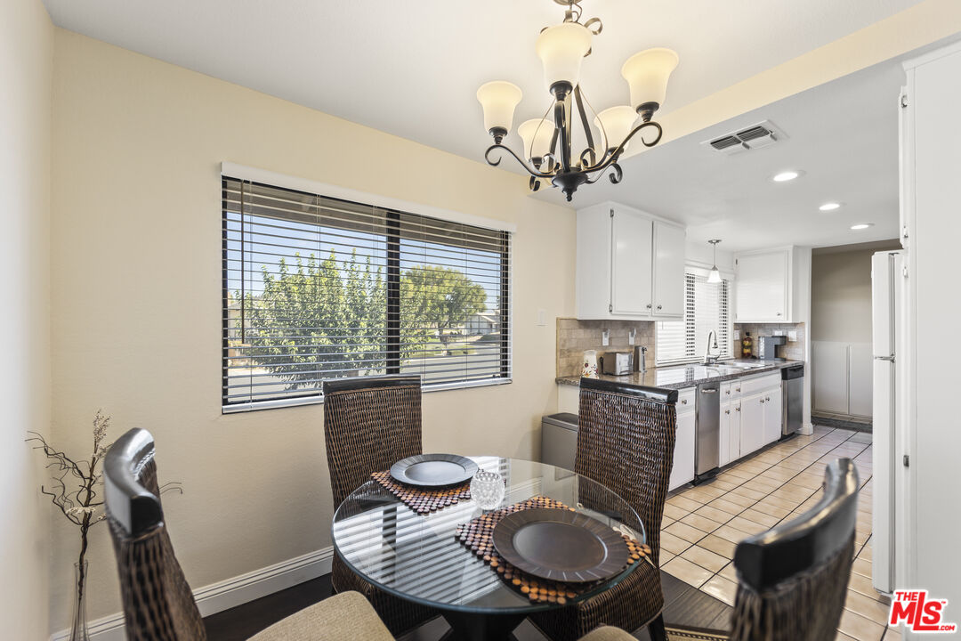12896 Rain Shadow Road Victorville, CA 92395 - Photo 11 of 39 a kitchen with stainless steel appliances granite countertop a stove a sink a dining table and chairs
