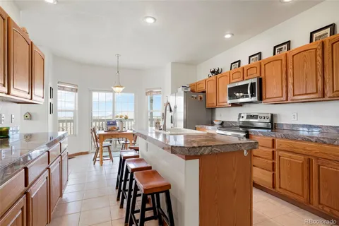 a kitchen with stainless steel appliances granite countertop wooden cabinets a dining table and chairs