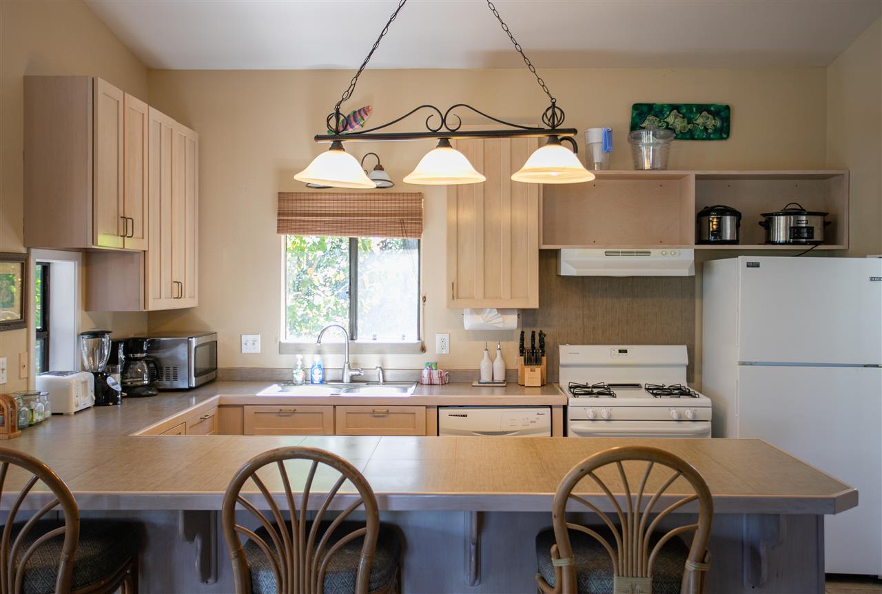 1555 West Kuiaha Road Haiku, HI 96708 - Photo 10 of 30 a kitchen with granite countertop a stove a sink a dining table and chairs