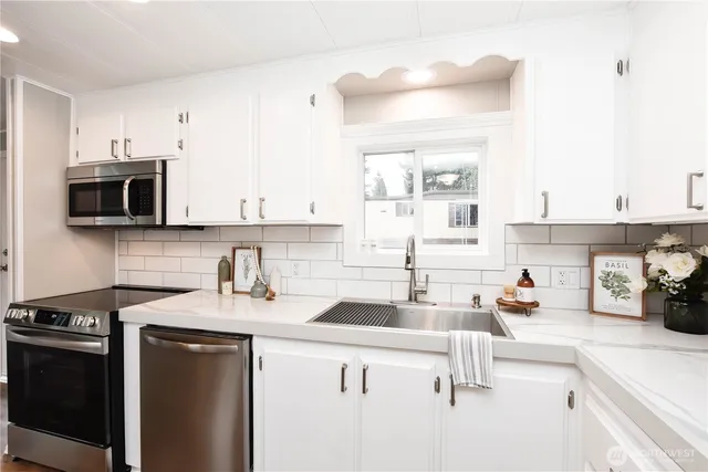 a kitchen with stainless steel appliances a sink a stove and white cabinets