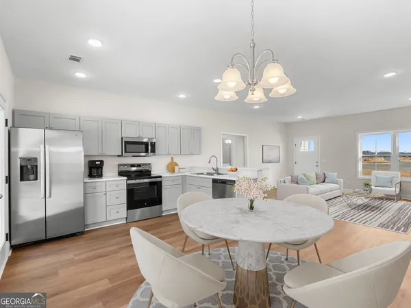 a kitchen with stainless steel appliances kitchen island granite countertop a dining table chairs and microwave