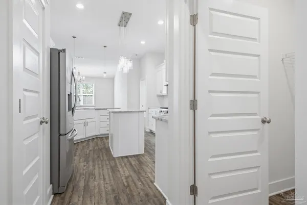 a kitchen with kitchen island granite countertop a stove a sink dishwasher and a refrigerator with wooden floor
