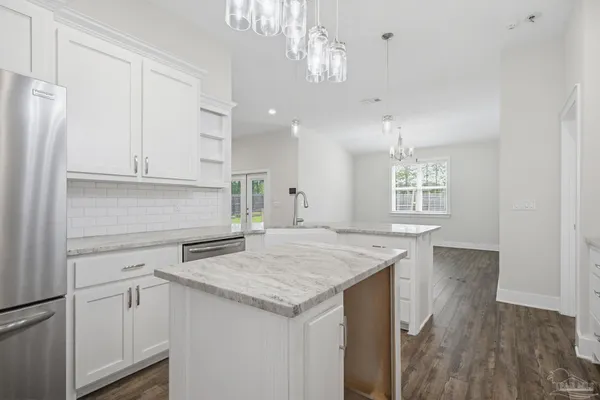 an empty room with wooden floor chandelier and windows