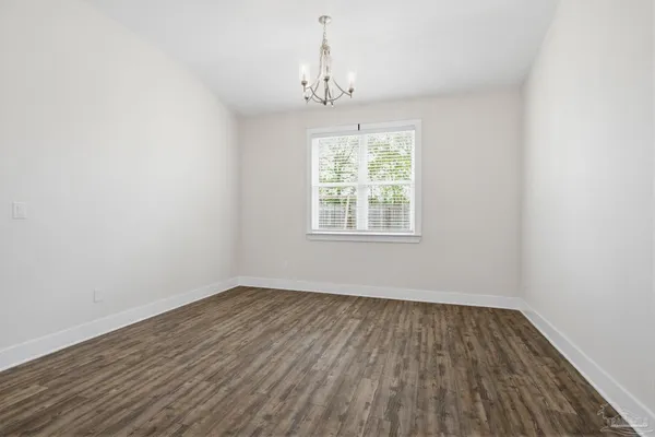 an empty room with wooden floor chandelier and windows