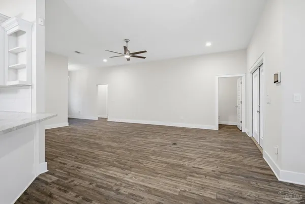 an empty room with wooden floor chandelier fan and windows