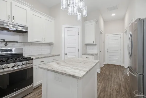 a kitchen with granite countertop a stove a sink and a refrigerator