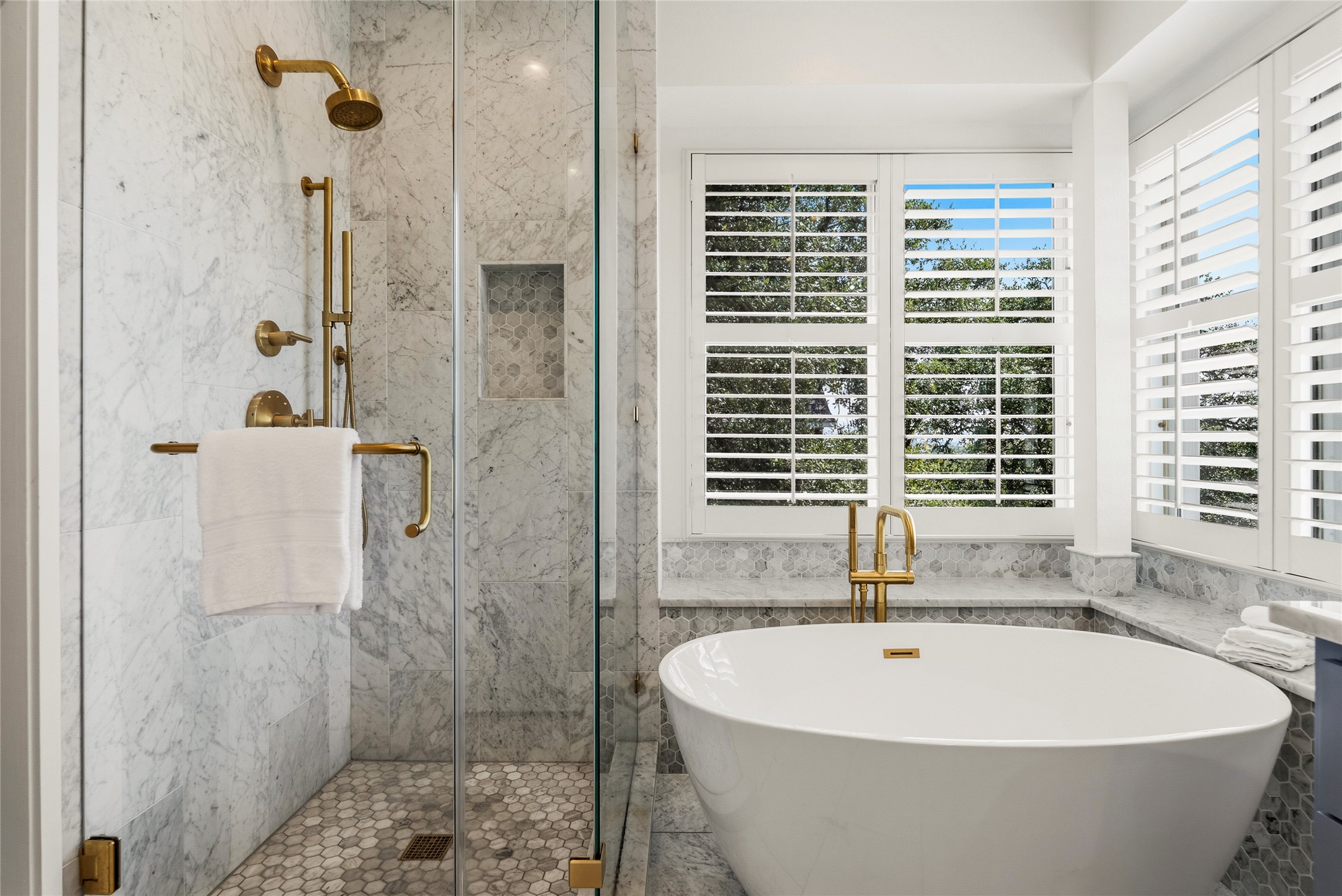 3107 Lookout Lane Austin, TX 78746 - Photo 25 of 39 Marble finishes and golden fixtures elevate a sleek, modern bathroom design.