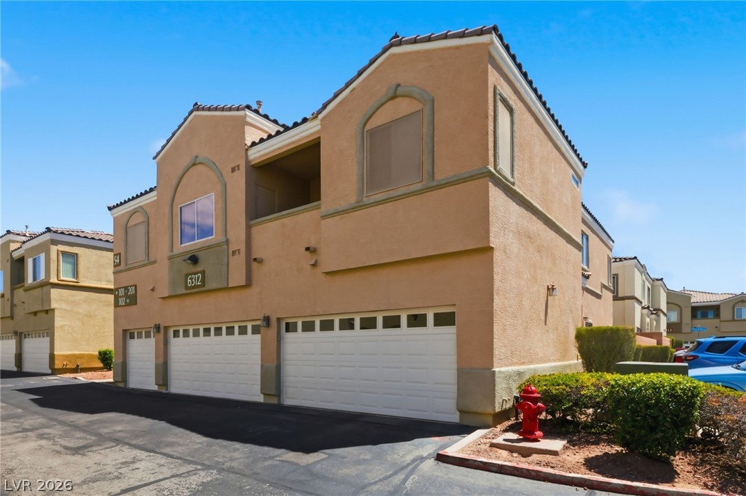 6312 Sandy Ridge Street, Unit 3102 North Las Vegas, NV 89081 - Photo 23 of 31 Multi-level residential building featuring integrated garages and a classic stucco exterior.