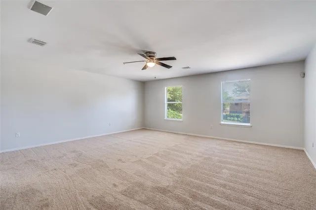 an empty room with windows and ceiling fan