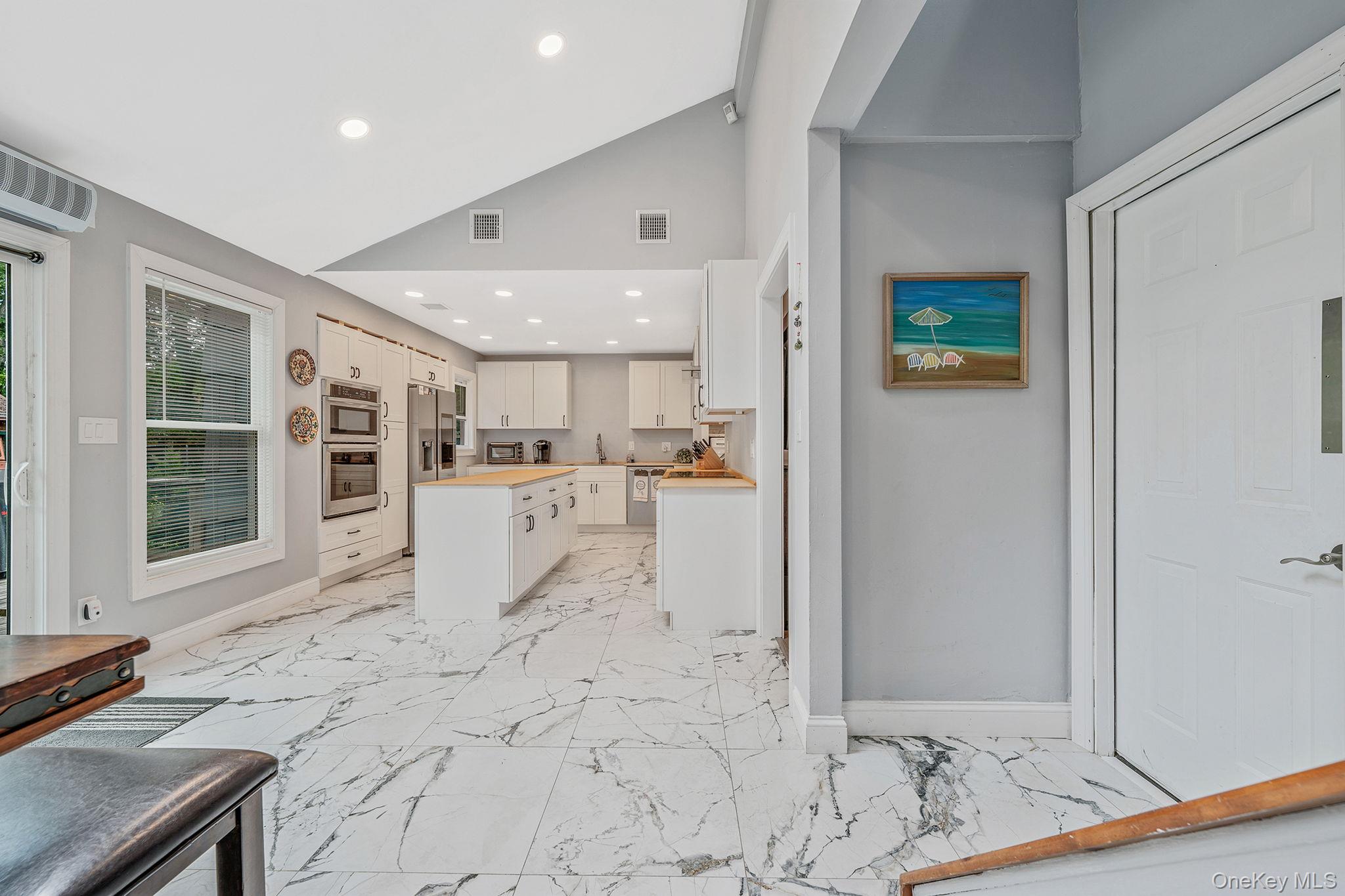 5 Hastings Drive Ridge, NY 11961 - Photo 11 of 31 a view of a kitchen with kitchen island a sink stainless steel appliances wooden floor and a counter top space