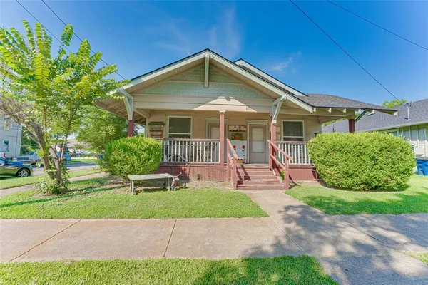 a front view of a house with a yard and potted plants