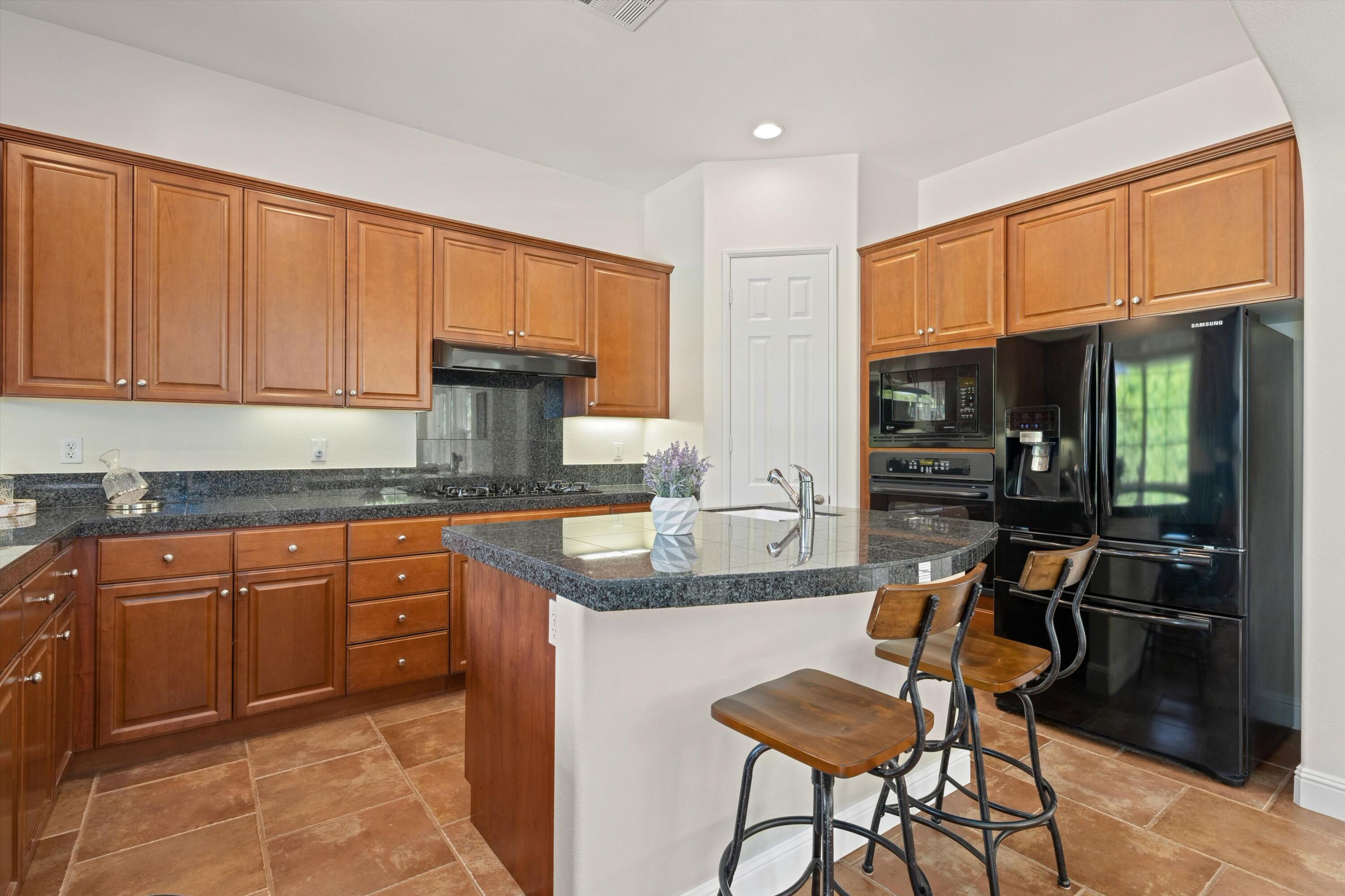 2 Via Santa Elena Rancho Mirage, CA 92270 - Photo 17 of 51 a kitchen with granite countertop wooden cabinets a dining table and chairs