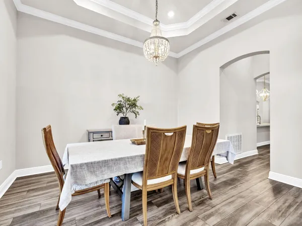 a dining room with wooden floor a chandelier a wooden table and chairs