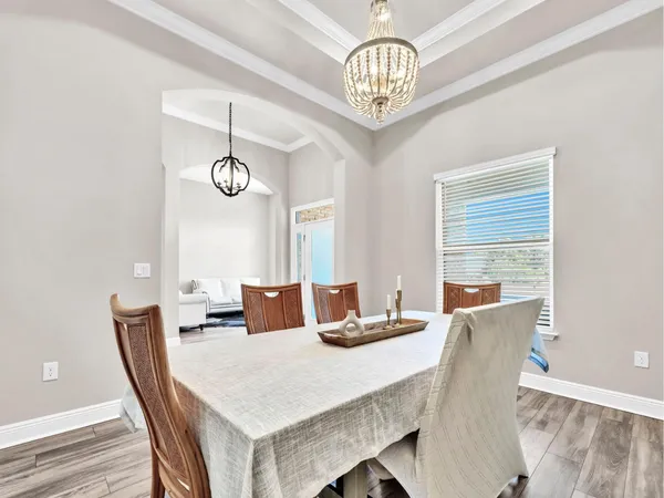 a view of a dining room with furniture a chandelier and wooden floor