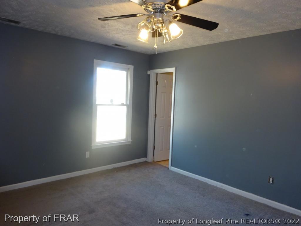 6528 Applewhite Road Fayetteville, NC 28304 - Photo 12 of 15 an empty room with windows and chandelier fan