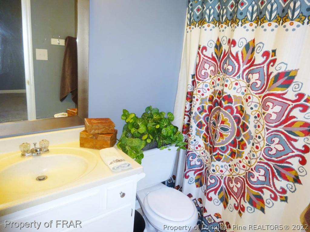 6528 Applewhite Road Fayetteville, NC 28304 - Photo 13 of 15 a bathroom with a sink mirror vanity and toilet