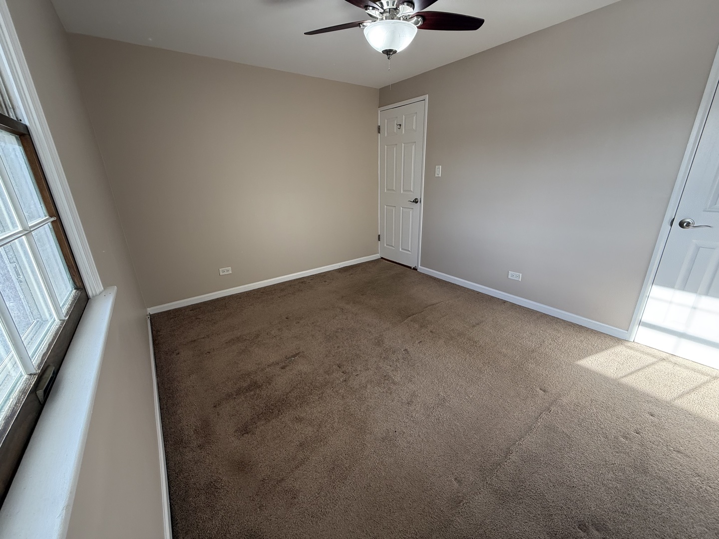 9060 South Main Street Hometown, IL 60456 - Photo 9 of 18 an empty room with a chandelier fan and windows