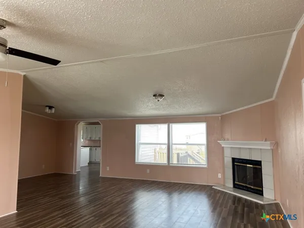 an empty room with wooden floor fireplace and windows