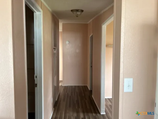 a view of a hallway with wooden floor and a bathroom