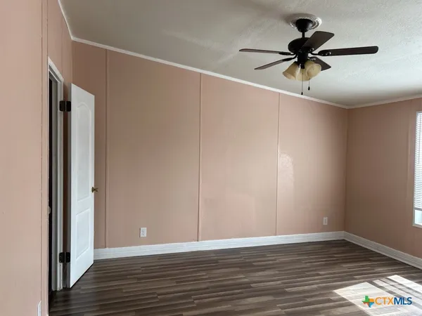 a view of room with wooden floor and a ceiling fan