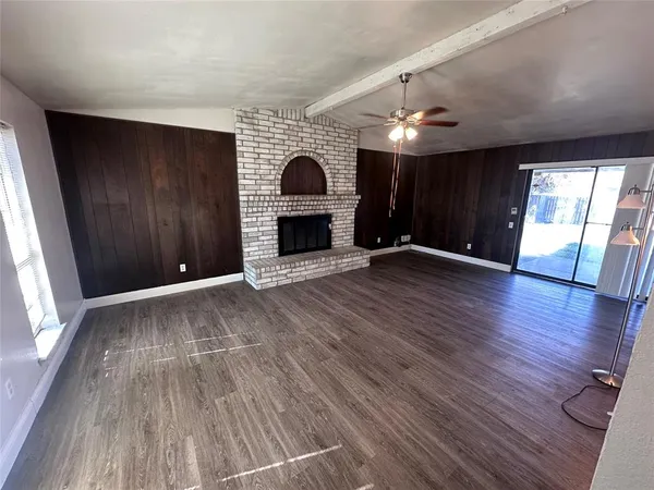 an empty room with wooden floor fireplace and windows