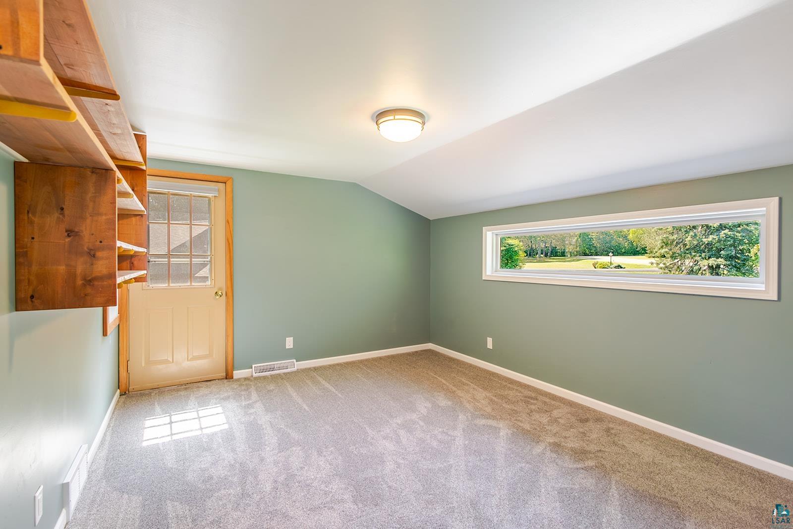 29 Ridge Road Esko, MN 55733 - Photo 21 of 41 Room featuring a horizontally-oriented window, built-in wooden shelving, a glass-paneled exterior door, wall-to-wall carpeting, and a flush-mount ceiling light