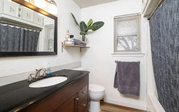 a bathroom with a granite countertop sink a toilet and a mirror