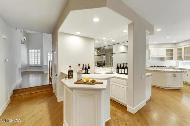 a kitchen with a sink dishwasher stove and white cabinets with wooden floor