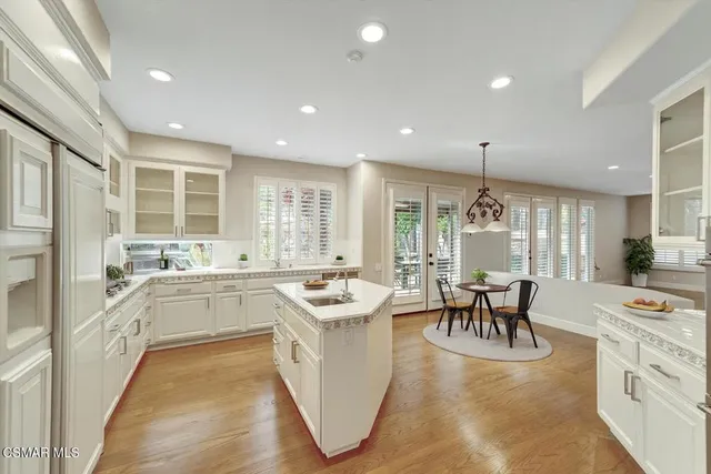 a large white dining hall with stainless steel appliances granite countertop a stove and a large window