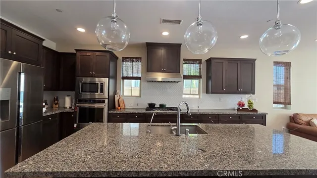 a kitchen with kitchen island granite countertop a sink stove and refrigerator