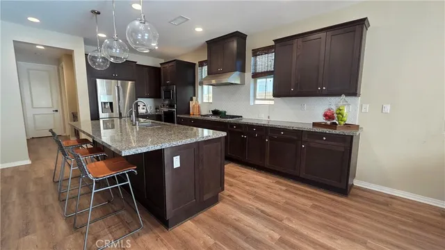 a kitchen with kitchen island granite countertop a sink cabinets and wooden floor