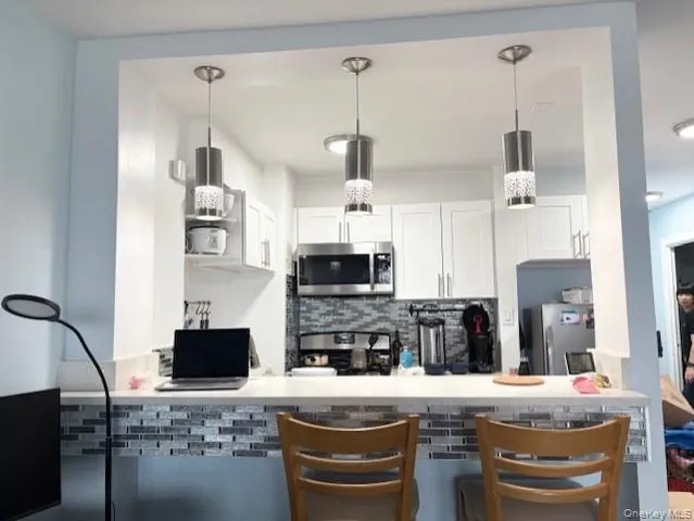 a kitchen with kitchen island granite countertop a stove top oven a sink a counter top space and cabinets