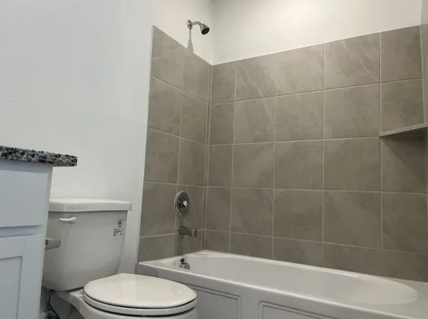 a bathroom with a granite countertop sink a toilet and bathtub
