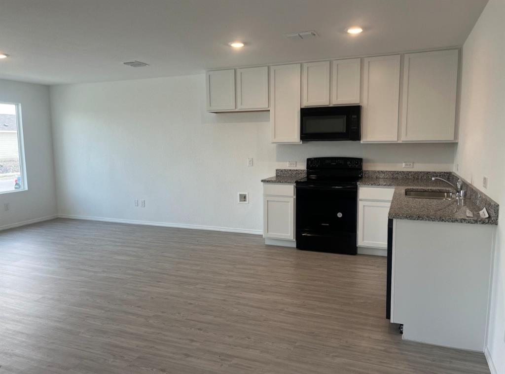 252 Jethro Lane Princeton, TX 75407 - Photo 5 of 20 a kitchen with granite countertop a refrigerator and a stove top oven
