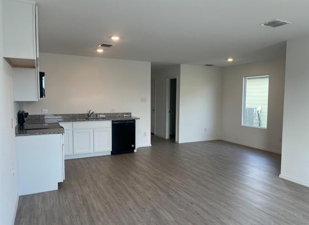 252 Jethro Lane Princeton, TX 75407 - Photo 6 of 20 a kitchen with wooden floors and white cabinets