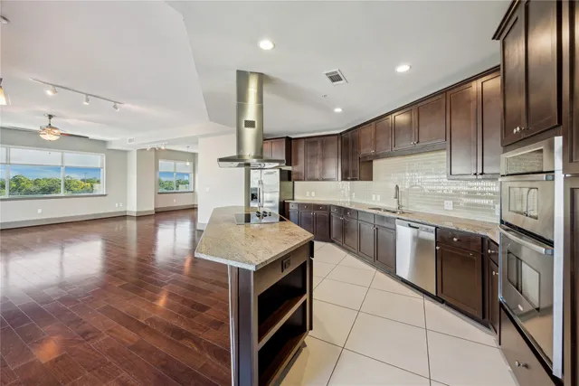 a kitchen with stainless steel appliances granite countertop a sink a stove and a refrigerator