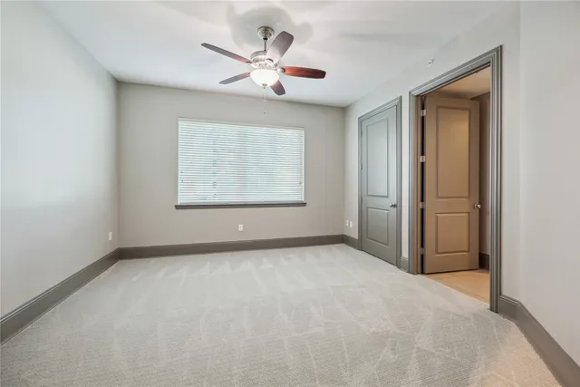 an empty room with chandelier fan and windows