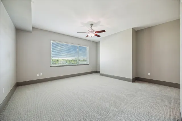 an empty room with chandelier fan and windows
