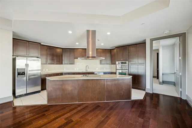 a large kitchen with stainless steel appliances granite countertop a large counter top a sink and a refrigerator