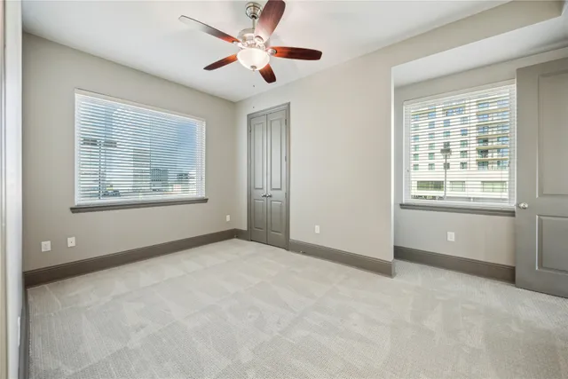 an empty room with chandelier fan and windows