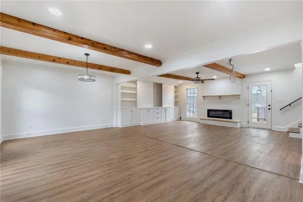an empty room with wooden floor fireplace and windows