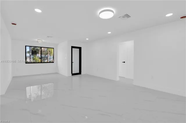 an empty room with windows and refrigerator