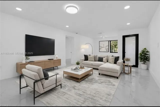 an empty room with windows and view of kitchen