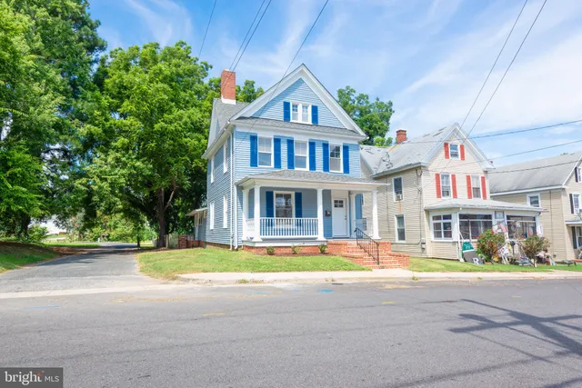 a front view of a building with garden and trees