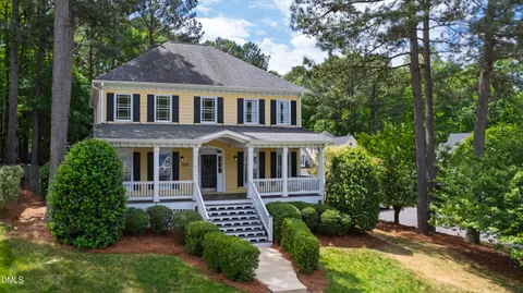 a front view of a house with a garden and trees
